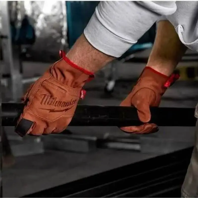 Worker wearing brown leather gloves while lifting a steel bar.