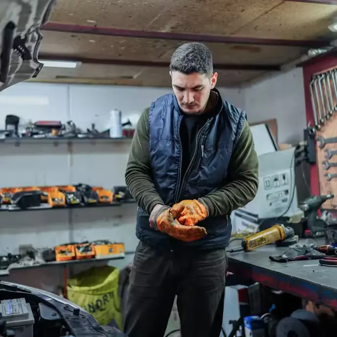 Mechanic wearing brown leather mechanic gloves in an auto workshop